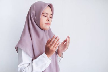 Gri arka planda dua eden Asyalı kadın