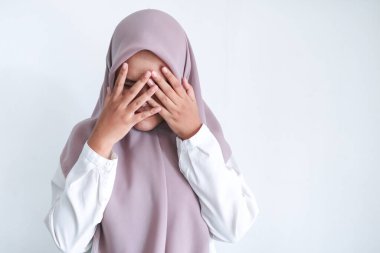 Yüzünü gri arka planda saklayan Asyalı kadın.
