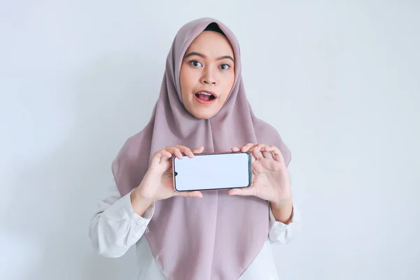 灰色の背景に携帯電話を示すアジアの女の子 — ストック写真