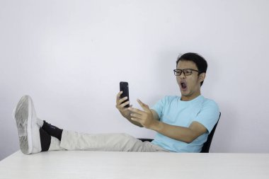 Genç Asyalı adam masanın üzerinde bacağı olan akıllı telefona baktığında şok olur.