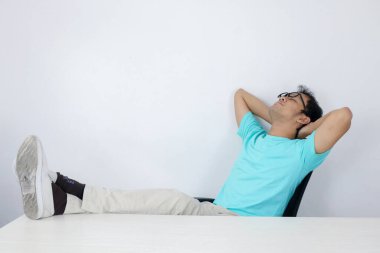 Sakin gülümseyen Asyalı genç adam rahat ofis koltuğunda rahatlıyor eller başının arkasında, mutlu adam işten sonra dinleniyor, gözleri kapalı eğleniyor, huzur içinde, stres olmadan.