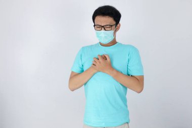 Kalp krizi geçiren Asyalı genç bir adam ya da soluk soluğa kalmış soğuk algınlığı. Cerrahi maske takıyor ve evdeki karantina sırasında göğsünün sıkıştığını hissediyor. Corona virüsü salgını.