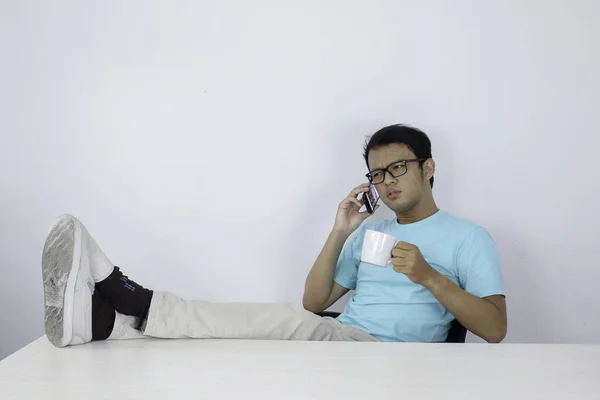 Mladý Asijský Muž Šokován Když Dívá Smartphone Nohou Stole — Stock fotografie