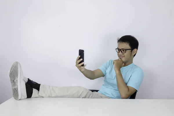 Genç Asyalı Adam Masanın Üzerinde Bacağı Olan Akıllı Telefona Baktığında — Stok fotoğraf