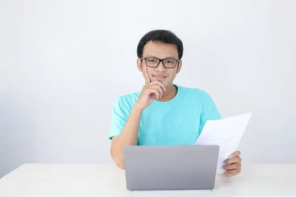 若いアジア人男性は ラップトップや文書で作業するときに笑顔と幸せです 青いシャツを着たインドネシア人男性 — ストック写真