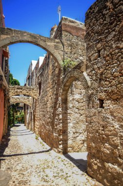 Ortaçağ Rodos 'unun dar sokaklarında kemer ve geçitlerle birbirine bağlı iki katlı tüccarlar ve zanaatkarlar var. Bu, bir deprem durumunda binaların istikrarını sağlar..   
