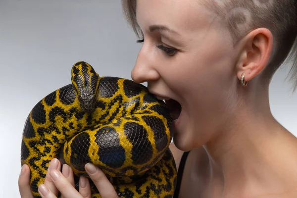 Woman biting yellow snake — Stock Photo, Image