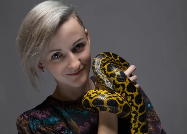 Blond smiling woman holding snake