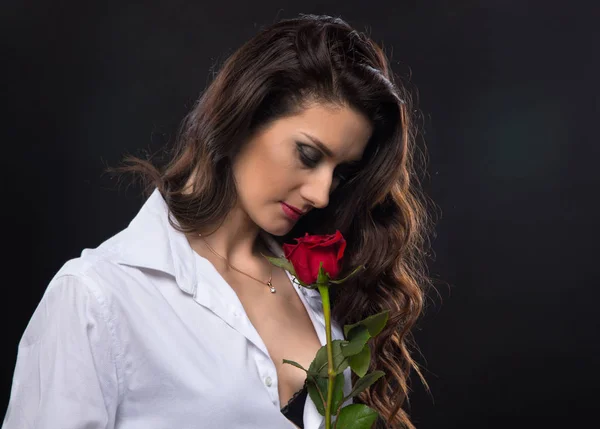 Brunetka kobieta kręcone, trzymając red rose — Zdjęcie stockowe