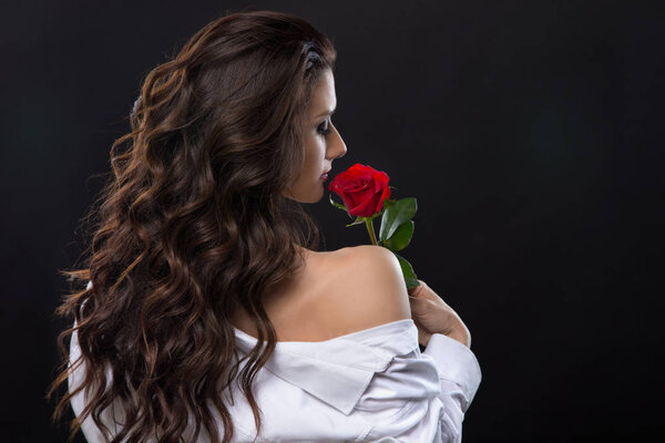 Beautiful brunette sniffing red rose