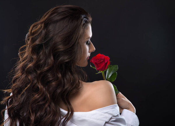 Beautiful brunette woman sniffing red rose