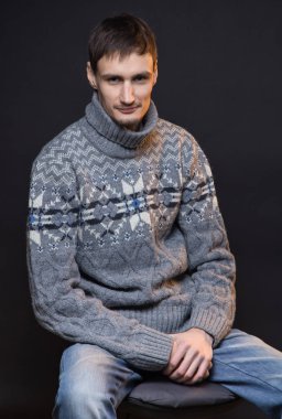 Örme kazak giyen gülümseyen esmer adam