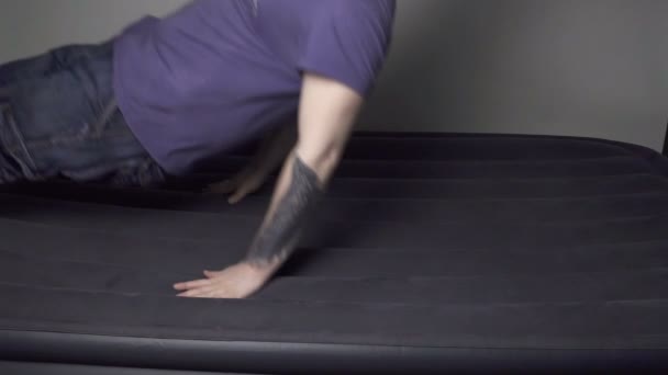 Müder Mann fällt auf aufblasbare Matratze — Stockvideo