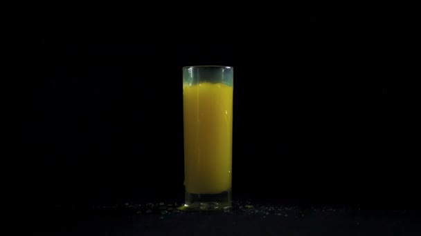 Падение льда в апельсиновом соке — стоковое видео