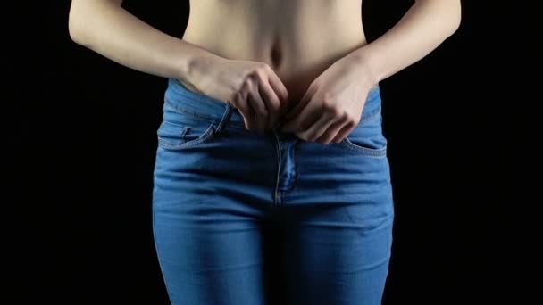 Молодая женщина снимает синие джинсы — стоковое видео