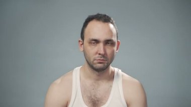 Gri arka planda traşsız üzgün bir adamın videosu