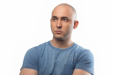 Kollarını kavuşturmuş düşünceli kel bir adamın fotoğrafı.