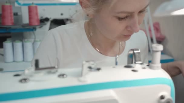 Video de la mujer rubia cosiendo en la máquina eléctrica en el taller — Vídeo de stock