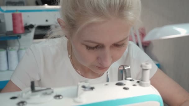 Vídeo de una joven cosiendo ropa en una máquina eléctrica en un taller — Vídeo de stock
