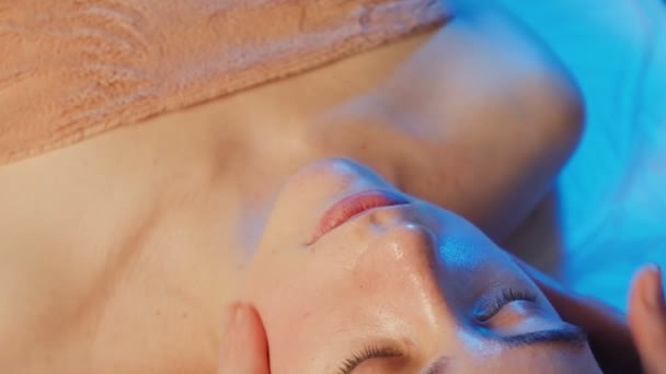 Молода дівчина отримує масаж обличчя в клініці — стокове відео