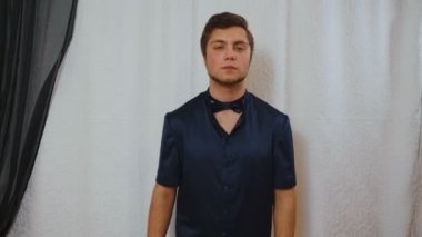 Evin içinde mavi ipek pijamalarla poz veren genç adamın videosu.