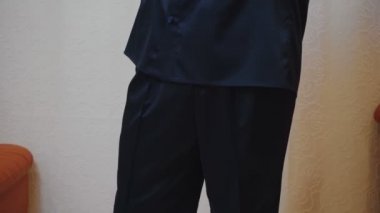 Evin içinde mavi ipek pijama giymiş genç bir adam.