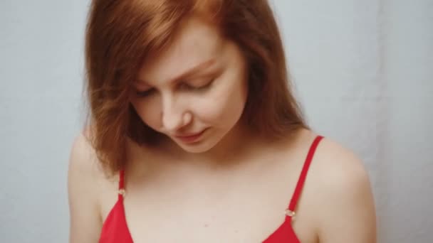 Gyömbéres fiatal lány piros selyem pizsamában otthon — Stock videók