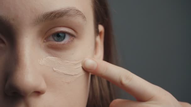 Jong meisje zet een stichting crème op haar gezicht — Stockvideo