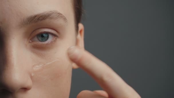 Jong meisje zet een stichting crème op gezicht met haar vinger — Stockvideo