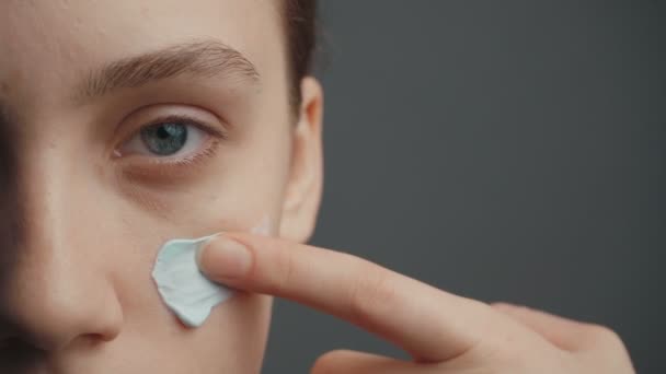 Молода жінка кладе на обличчя косметичну блакитну глину — стокове відео