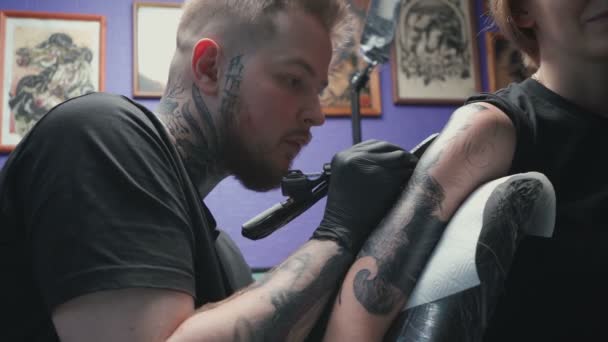Видео, где мужчина делает черную татуировку змеи для женщины в студии — стоковое видео