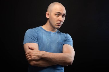 Photo of young bald man in blue tee shirt with arms crossed