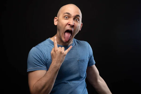 Zdjęcie łysego mężczyzny w niebieskiej koszuli z językiem i kozim gestem — Zdjęcie stockowe
