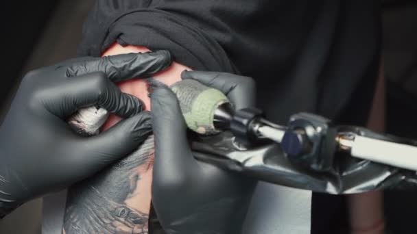 Видео, где молодой татуировщик делает татуировку змеи для женщины — стоковое видео