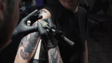Footage of man doing tattoo of snake in studio