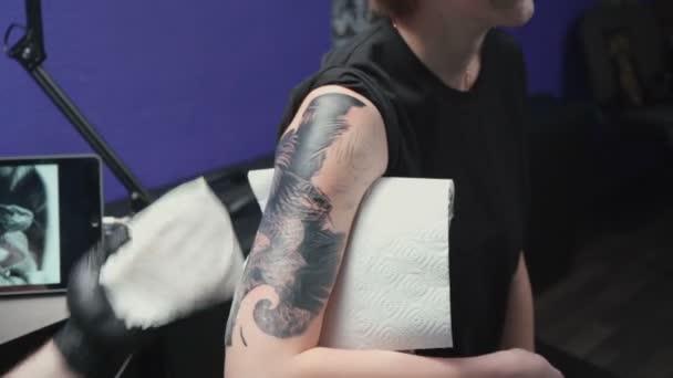 Запись мужчины, делающего тёмную татуировку для женщины в студии — стоковое видео
