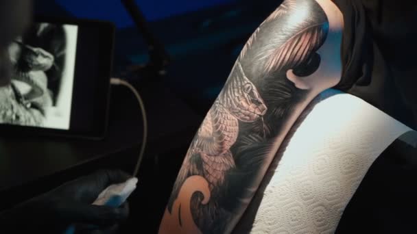 Закрыть видео, как мужчина делает черную татуировку на женщине — стоковое видео