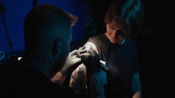 Tiro de homem fazendo tatuagem de cobra em mulher no estúdio — Vídeo de Stock