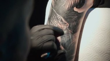 Close up video of doing black tattoo on woman in studio