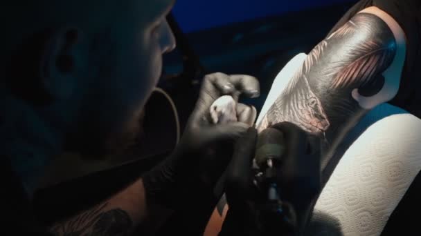 Close up video of man doing black tattoo of snake for woman in studio — Stok video