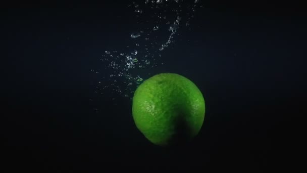Schießen auf fallende Avocado im Wasser auf schwarzem Hintergrund — Stockvideo