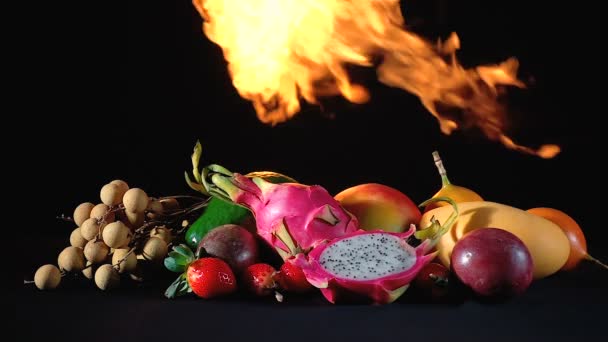Video exotic fruits in the fire on black background — Stockvideo