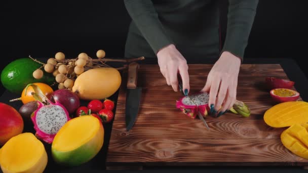 Vidéo de femme coupe des fruits du dragon sur une planche en bois — Video