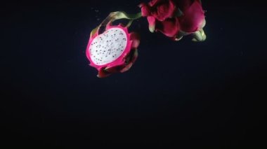 Pitahaya 'nın yarısını kara arka planda suya düşürmek.