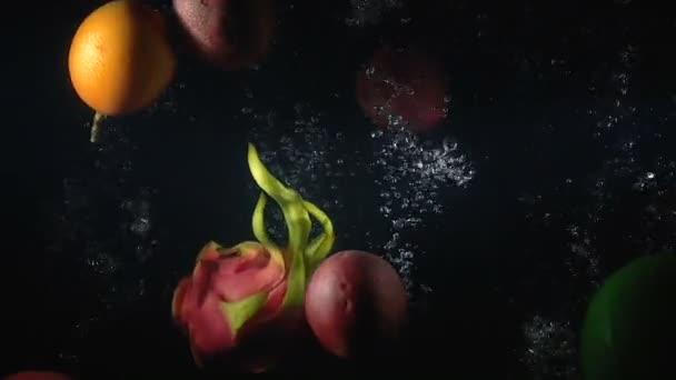 Video falling exotic fruits in the water on black background — Stock Video