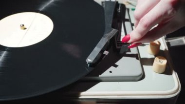 Kırmızı tırnaklı bir kadının retro gramofonu açtığı görüntüler