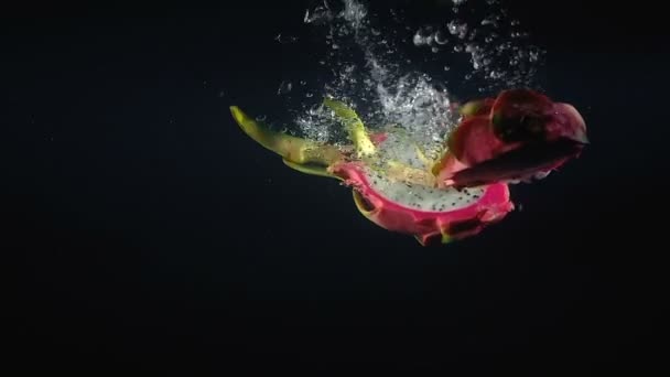 Video cayendo la mitad de pitaya en el agua sobre fondo negro — Vídeo de stock