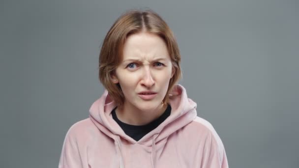 Schieten van jonge verwarde vrouw in roze sweatshirt — Stockvideo
