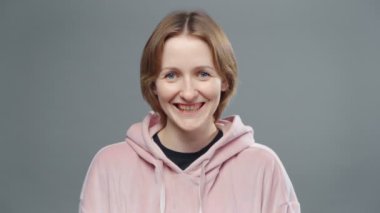 Pembe kazaklı, gülen genç bir kadını vurmak.