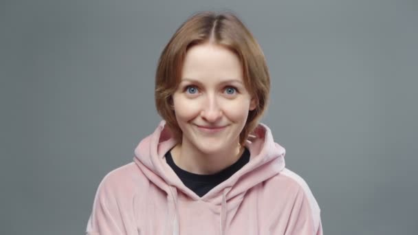 Erschießung einer jungen nickenden Frau in rosa Sweatshirt — Stockvideo